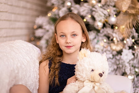 girl holding white bear plush toy sitting on sofa thumbnail
