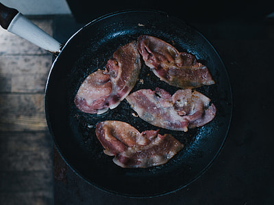 four strip of bacon frying on black skillet thumbnail