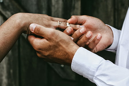 man putting wedding band on person hand thumbnail