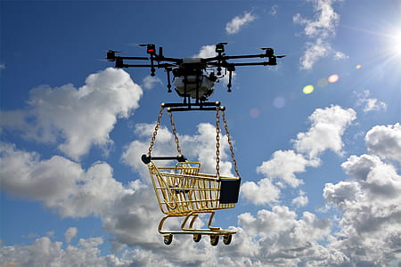 white and black drone lifting yellow shopping cart during daytime thumbnail