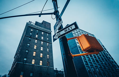 low angle photo of One Way sign near gray building thumbnail