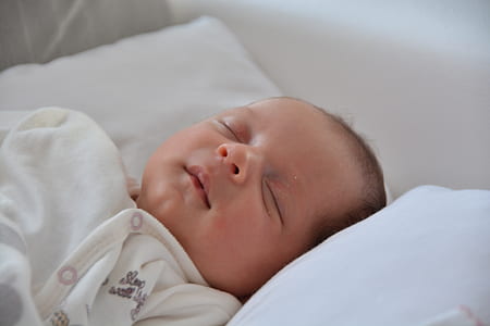 sleeping baby laying on white pillow thumbnail