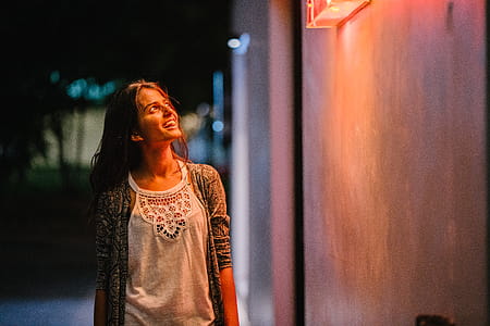 Woman in Gray Cardigan Standing Near Wall during Nighttime thumbnail