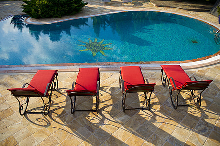 photo of red-and-black pool loungers beside swimming pool thumbnail