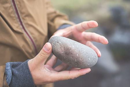 close-up photography of person holding gray stone thumbnail