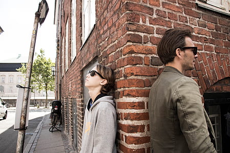 man leaning against wall beside woman thumbnail