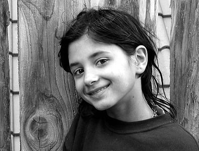 grayscale photo of girl wearing shirt leaning on wooden wall thumbnail