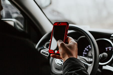person holding smartphone in front of steering wheel thumbnail