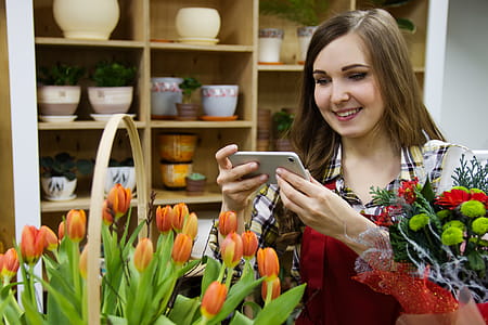 Woman Taking a Photo of Orange Tulips thumbnail