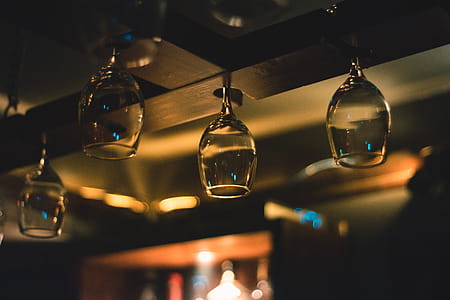Selective Focus Photography of Wine Glass Hanging on Black Wooden Rack thumbnail
