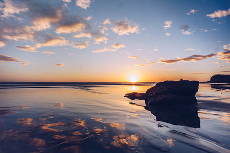 rock formation on calm water during golden hour thumbnail