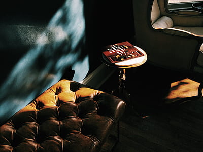 brown board game near tufted brown leather ottoman inside room thumbnail