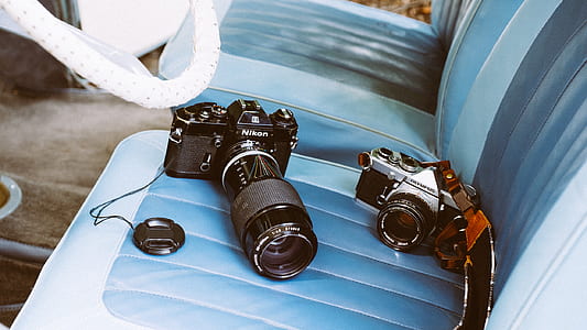 two black-and-silver DSLR cameras on car seat thumbnail