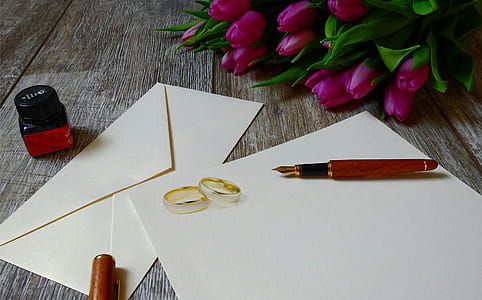 Photo of wedding rings sitting on blank wedding invitations. thumbnail