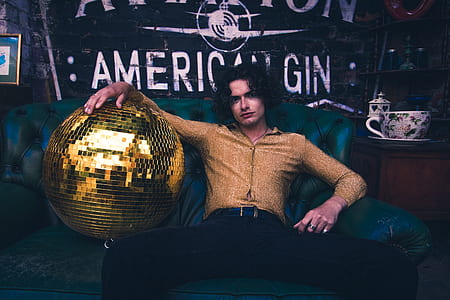 man sitting on sofa beside disco ball thumbnail