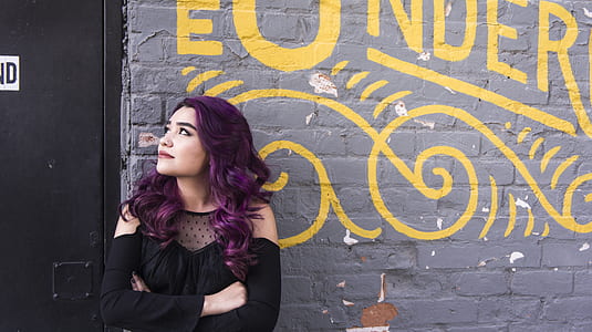woman wearing black top leaning on gray wall thumbnail