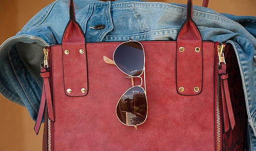 black sunglasses hanging on red leather bag thumbnail