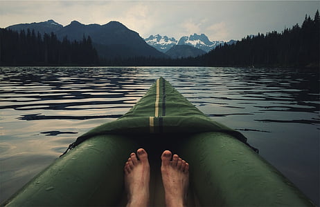 person in green kayak overlooking mountains at lake thumbnail