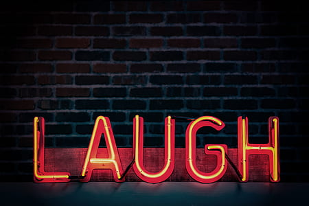 red laugh neon light sign against black brick background thumbnail