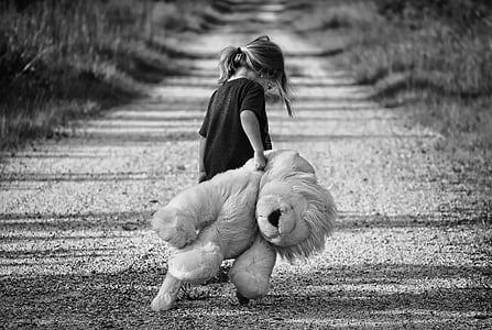 girl in black crew-neck shirt holding lion plush toy in grascale photography thumbnail