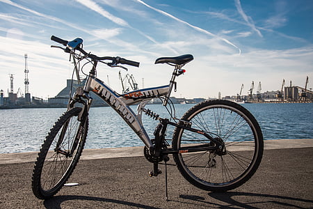 black and gray full-suspension mountain bike parked near body of water thumbnail