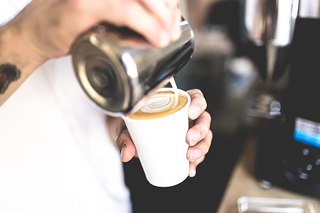 person pouring white milk on brown cafe thumbnail