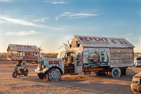 white single cab stake truck near motor scooter under blue sky and white clouds during golden hour thumbnail