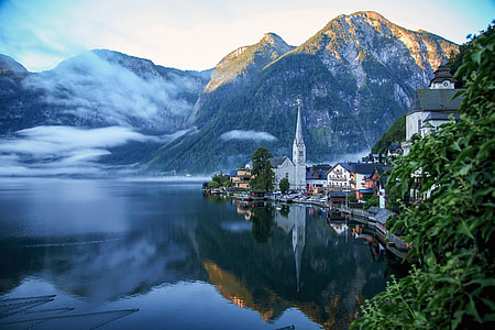 landscape photography of riverside town near mountains under clear sky during daytime thumbnail