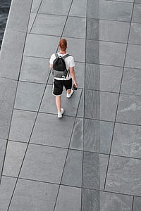 person walking on gray concrete pavement while holding black camera thumbnail