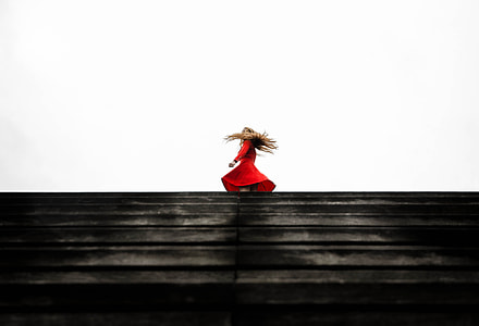 woman wearing red long-sleeved dress standing on top of stairs during daytime thumbnail