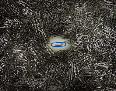 blue paper clip in the middle of pile of grey paper clips thumbnail