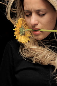 woman wearing black zip-up top biting yellow sunflower thumbnail
