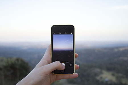 person taking picture of field with yellow iPhone 5c thumbnail