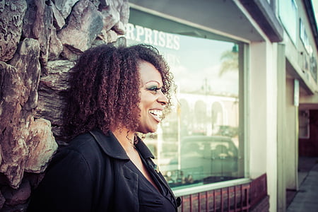 woman in black top standing near window smiling thumbnail