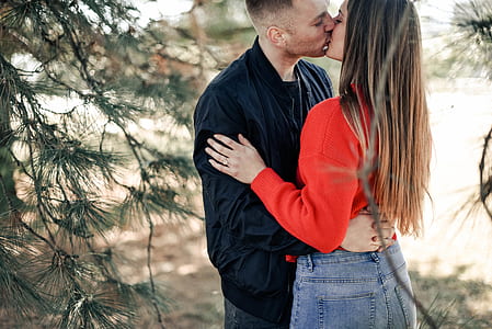 man and woman kissing near green leaf tree during daytime thumbnail