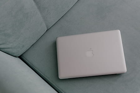 MacBook laptop lying on mint couch thumbnail