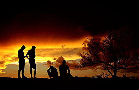 silhouette photo of two person standing in front of two person sitting on ground thumbnail