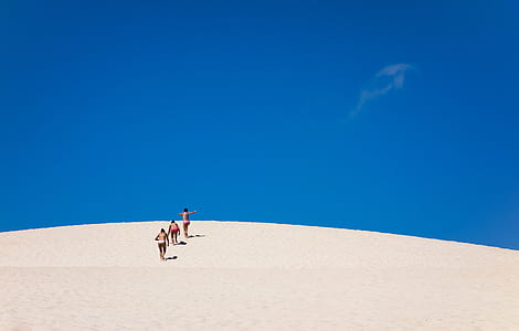 three people walking on sand dune thumbnail