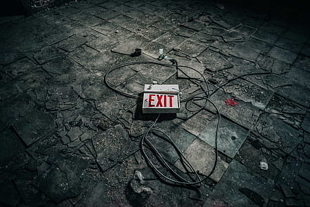white exit signage with gray cords on gray tiled pavement thumbnail