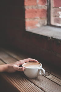 person holding white ceramic cup with brown coffee thumbnail
