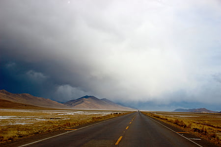 empty highway overlooking mountain under white cloudy skies at daytime thumbnail