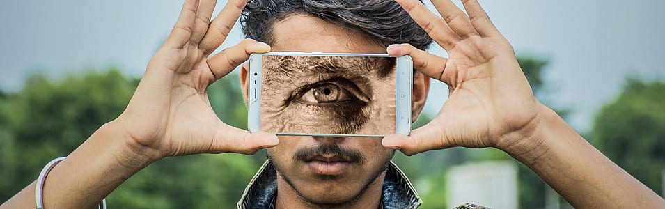 person holding white Android smartphone displaying eye thumbnail