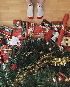 person standing in front of holiday tree and assorted gifts thumbnail