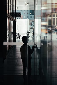 boy standing beside glass wall thumbnail