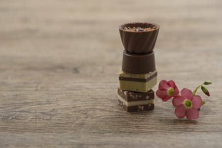 balance chocolate cake beside pink 5-petaled flower on wooden surface thumbnail