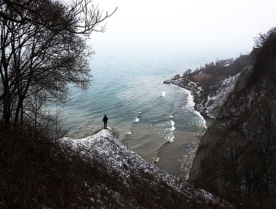 person standing on top of hillside looking on shoreline during daytime thumbnail