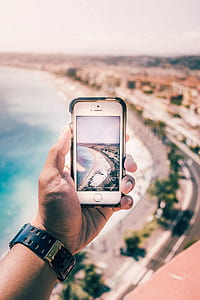 selective focus photography of person taking picture of seashore using silver iPhone 5s during daytime thumbnail