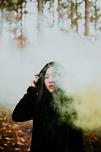woman in black jacket standing in the forest covered with smoke bomb thumbnail