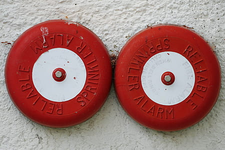 two white-and-red alarms on white wall thumbnail