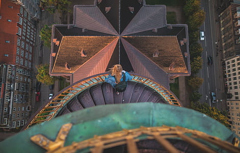 bird'e eyeview photo of woman standing on stairway facing buildings thumbnail